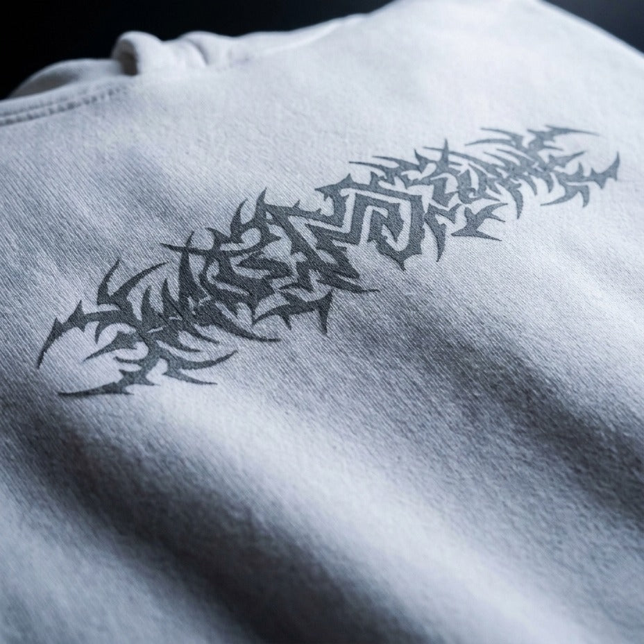 A close-up of a white sweatshirt featuring a stylized gray graphic print across the chest.